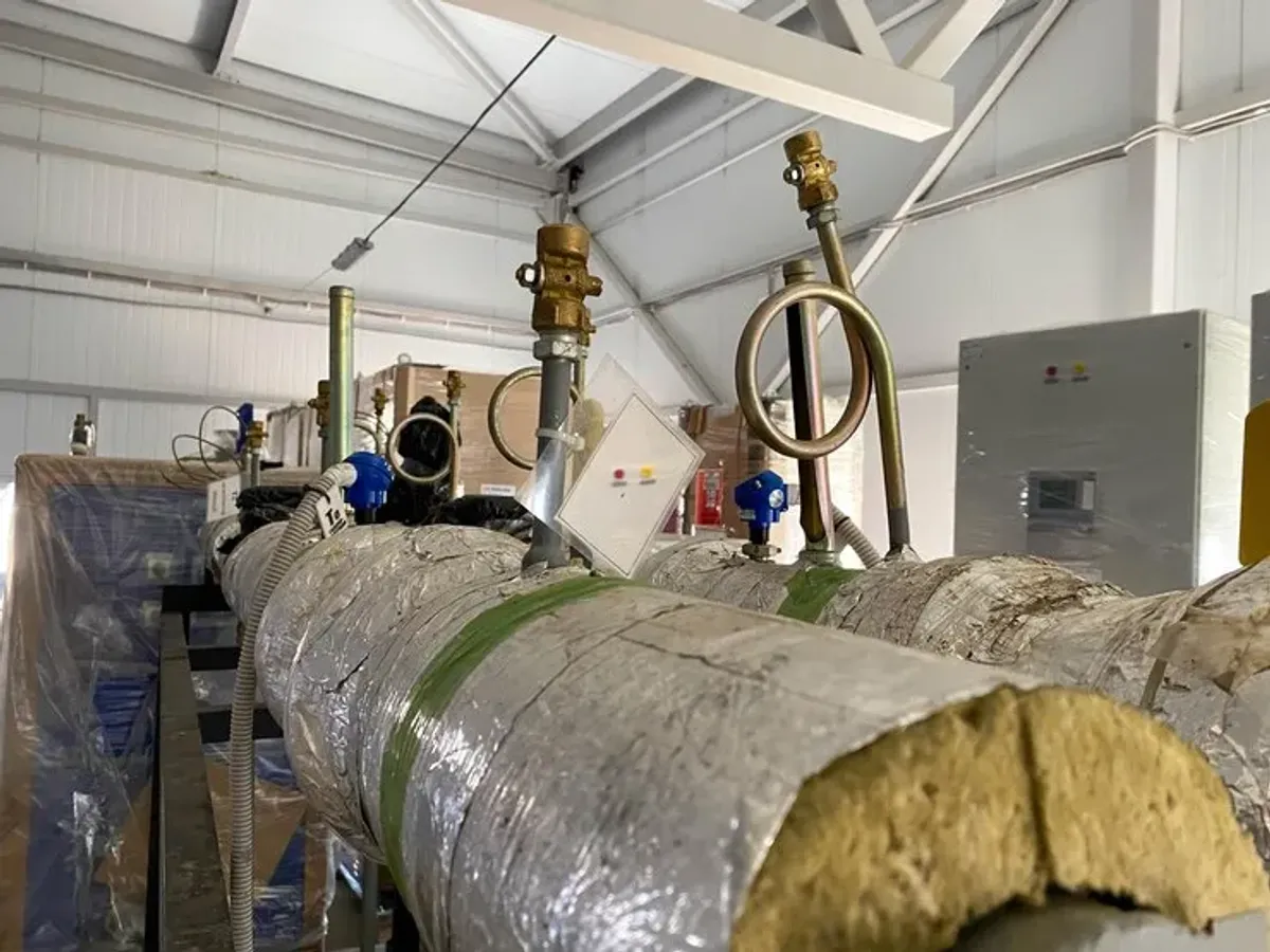 工业厂房内工艺管道特写，采用岩棉和铝箔进行绝热；配备阀门和传感器，以减少能量损失并保持安全——纳瓦公司施工。