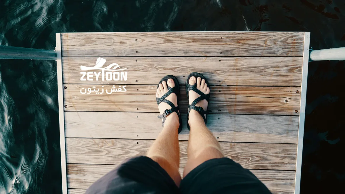 Su kenarında ahşap yüzeyde duran erkek ayağı, terlik giyiyor