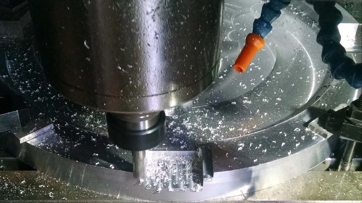 纳瓦工业车间内金属部件的数控铣削操作特写，伴有切屑和冷却喷嘴；部件的精密制造与最终精加工。