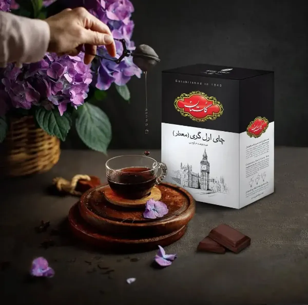 بسته چای ارل گری معطر گلستان در کنار فنجان چای تازه‌دم و شکلات